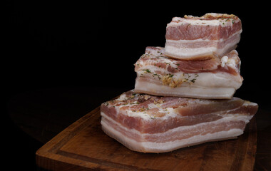 Appetizing salty lard with layers of meat with garlic and herbs. Delicious lard on a wooden cutting board.