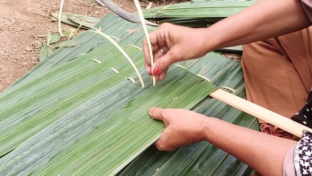 A Woman Is Making A Roof Out Of Nipa Leaves During The Day