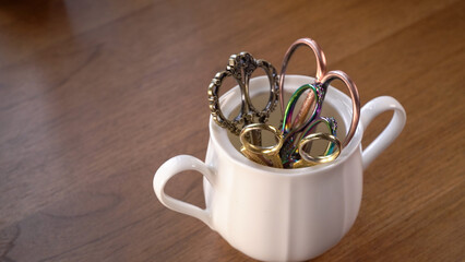 Vintage Scissors Collection in a Cup on Wooden Table