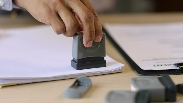 Businessman working on paperwork and stamping approvals, signing documents.