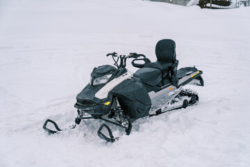 Black snowmobile stands on a snowy track