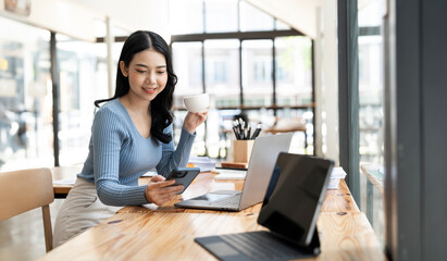 Charming  Caucasian smiling brunette woman looking and chatting on smartphone sitting at co-workspace. Concept of lifestyle, use technology