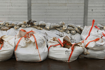 Hochwasserschutz, Sandsäcke und Big Bags vor einer mobilen Hochwasserschutzwand