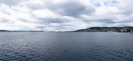 Skyline of Hobart (right) on the banks of the Derwent River in Tasmania. Cloudy sky. Widescreen image