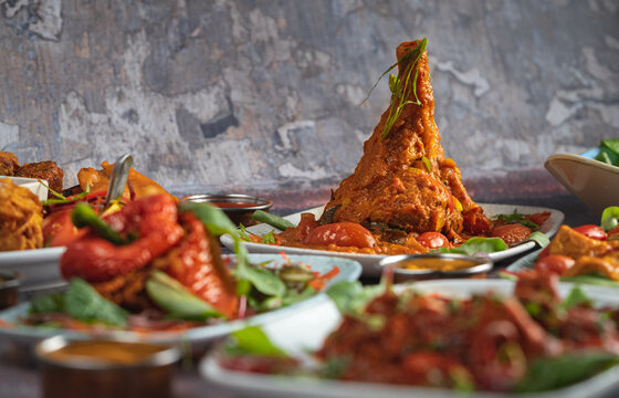 Spicy Lamb Shank with herbs and tomato sauce served with more foods on a table.