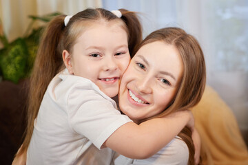 Happy loving family. Mother and her teenager daughter child girl playing and hugging in living room with flowers
