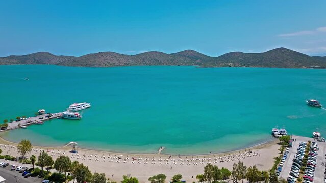 Scenic beach with calm turquoise water on the Island of Crete in Greece in 4K. Greek Paralia Schisma Elountas Compact Beach. Calm waters pedal boat umbrella rentals by Mediterranean Sea