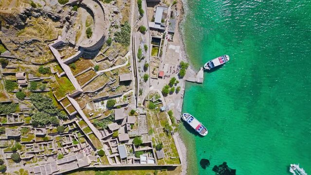 Scenic Aerial view of antique Fortress Island in Crete, Greece with tourists visiting. Spinalonga barren arid rocky islet in Elounda. Venetians built bastion-type seaward fortresses in Mediterranean