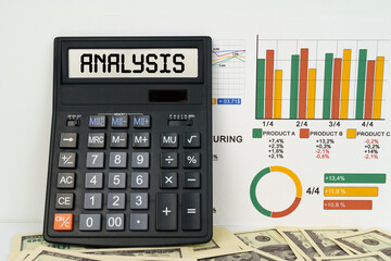 On the table are financial reports, dollars and a calculator with the inscription - ANALYSIS