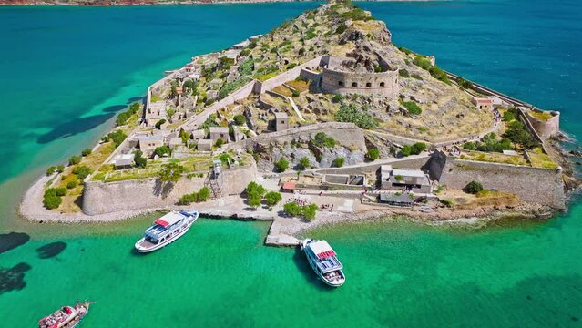 Scenic Aerial view of antique Fortress Island in Crete, Greece with tourists visiting. Spinalonga barren arid rocky islet in Elounda. Venetians built bastion-type seaward fortresses in Mediterranean