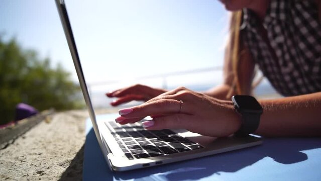 Woman laptop sea. Working remotely on seashore. Happy successful woman female freelancer working on laptop by the sea at sunset, makes a business transaction online. Freelance, remote work on vacation