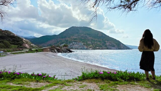 Aerial view of a free woman standing on a cliff of a seashore in Paralia Fodele. Drone view of a girl enjoying the view of Fodele Beach in Crete, Greek Island.