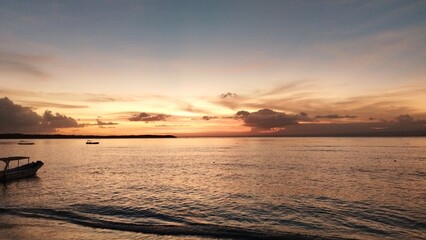 Serene sunset over calm ocean waters, small boats gently bobbing near shore.