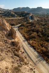 Dirt road in arid desert landscape with distant cliffs and morning sunlight, Elche, Alicante province, Spain - Stock photo