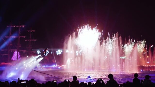 Flying on a flyboard in zhuhai in china in the evening during a performance with fireworks in the background