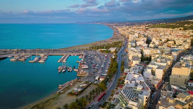 Aerial view of Rethymno beach with colourful umbrellas, crystal clear water, and golden sand with 12 Blue Flags. Rethymno with  archaeological sites, Byzantine churches and cosmopolitan resorts