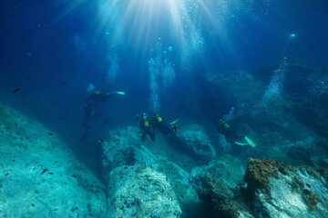 Scuba diving, scuba divers with sunlight and bubbles underwater in the Mediterranean sea, France, Occitanie - obrazy, fototapety, plakaty