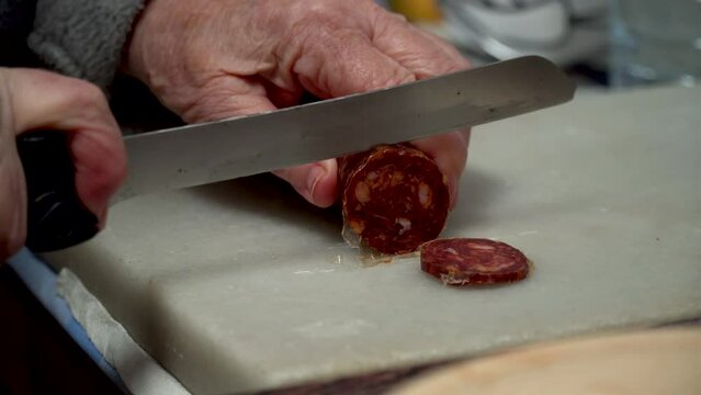 Closeup, person slicing chorizo