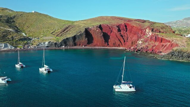 Aerial view of Red beach in Santorini surrounded by red hills and volcanic rocks. Rock formations with volcanic rocks, red pebbles, and sand of various colours, marine life for snorkelling lovers.