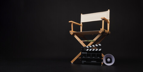 White director chair with clapper board and megaphone on black background.

