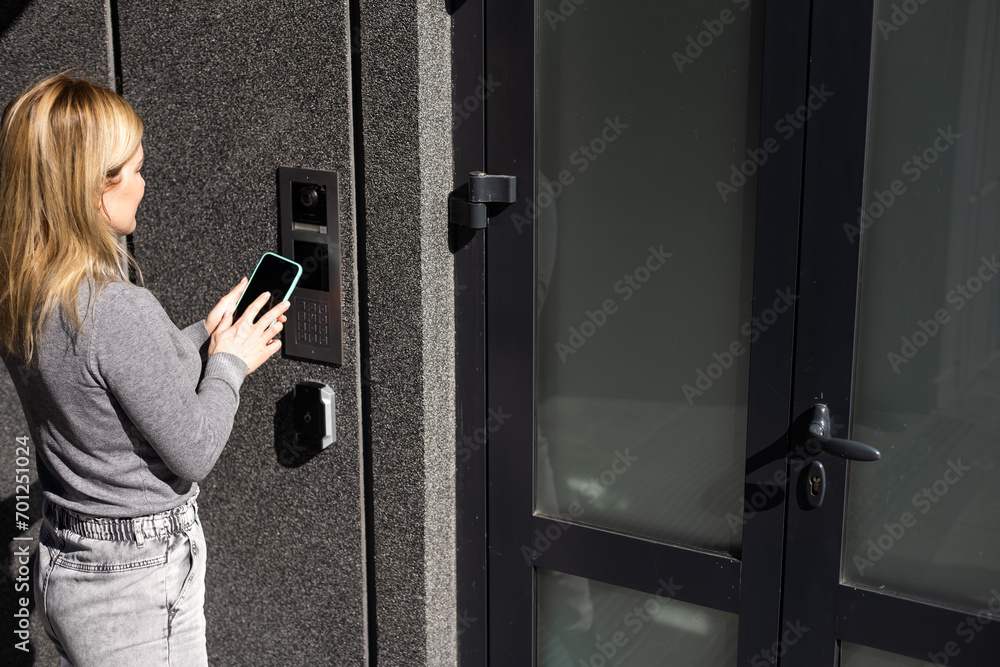 Poster woman locking smartlock on the entrance door using a smart phone. concept of using smart electronic 