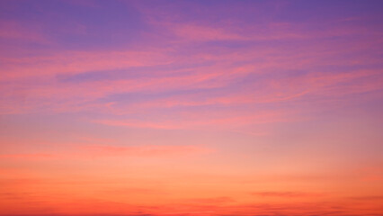 Sunset sky background with beautiful pink sunset clouds on colorful yellow, orange, and blue purple...