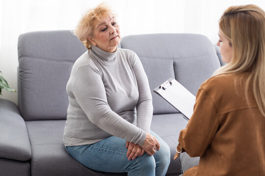 Depressed senior woman talking with female psychologist