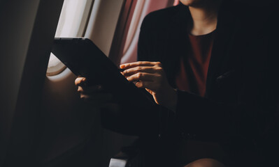 Blonde female tourist checking incoming notification on smartphone sitting on seat of airplane with...