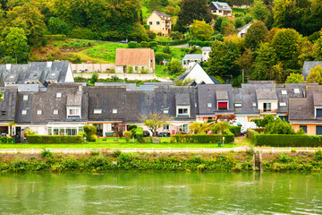 Obraz premium The coast of the Seine River in France in the suburbs of Rouen with beautiful private houses and dense green vegetation.