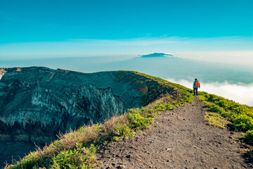 A hiker at the summit of Mount Ol Doinyo Lengai with the volcanic crater - the ash pit in Ngorongoro Conservation in Tanzania © martin