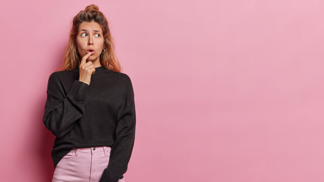 Photo of impressed young woman keeps mouth opened from wonder reacts to something amazing dressed in casual clothes feels stunned isolated over pink background copy space for your advertising content