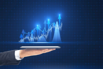 Close up of male hand holding tablet with growing forex chart with bright upward arrow on blurry pixel background. Success, financial growth and trade concept.