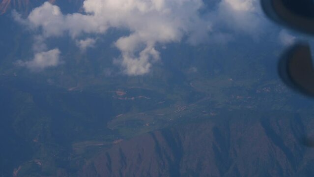 Panning from snowy mountains to hilly ground level from sky, with airplane propeller