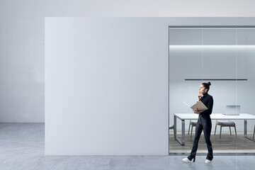 Blurry happy young female walking in modern light concrete and glass office box interior with mock...