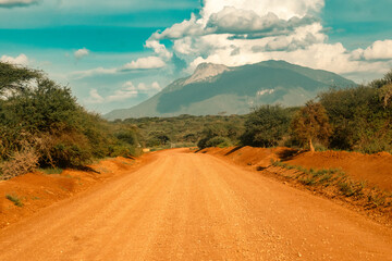 A dirt road against the background of Mount Longido in Tanzania - obrazy, fototapety, plakaty