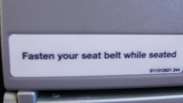 Please fasten your seatbelt while seated, safety standard instruction written on an airplane seat