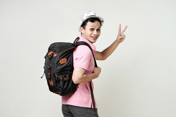 happy asian man backpacker give victory finger sign gesture. digital nomad and travelling concept. on isolated background.
