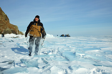 A man is a traveler behind the transparent ice floe of the frozen Lake Baikal. Winter trip. 