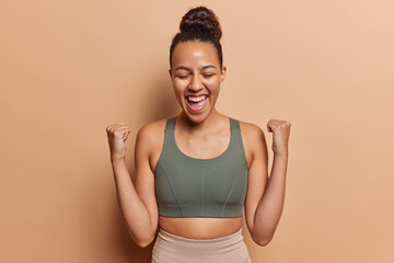 Waist up shot of optimistic young woman does sport regularly wears cropped top and leggings...