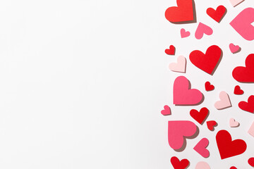 Small red and pink paper hearts on a light background. Valentine's Day. Top view. Space for text.
