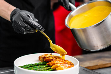 Professional chef cooking Baked fresh asparagus with wrapped meat in restaurant kitchen