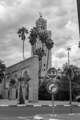 Photo of the tower of the Koutoubia Mosque. In the photo there is a stop sign written in Arabic. Cloudy day.