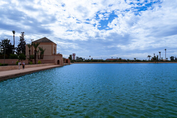 Photo of the Menara Gardens in the city of Marrakech. Photo of the lake with the house at the end of the lake. The house reflected in the lake. Cloudy day.