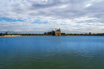 Photo of the Menara Gardens in the city of Marrakech. Photo of the lake with the house at the end of the lake. The house reflected in the lake. Cloudy day.