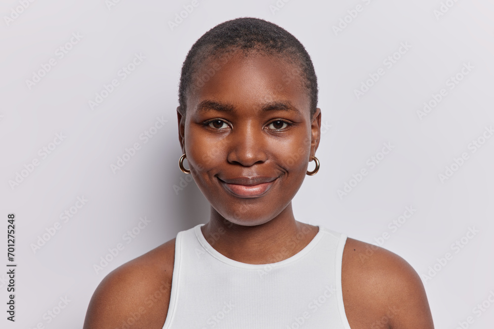 Poster Portrait of lovely short haired woman smiles gently looks delighted at camera has satisfied happy expression wears casual t shirt isolated over white background. People and face expressions concept