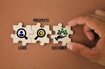 wooden puzzle with icons and the words Leads, Prospects, Customer.