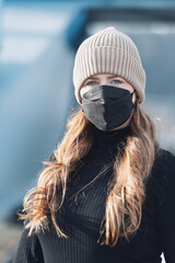 Woman with red long hair, blue eyes, young with FFP2 mask, wearing beige cap and black sweater,...