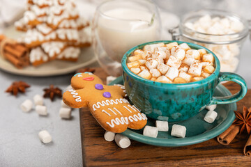 Hot drink with marshmallows and candy cane in cup on texture table.Cozy seasonal holidays.Hot cocoa with gingerbread Christmas cookies.Hot chocolate with marshmallow and spices.Copy space.