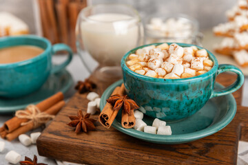 Hot drink with marshmallows and candy cane in cup on texture table.Cozy seasonal holidays.Hot cocoa with gingerbread Christmas cookies.Hot chocolate with marshmallow and spices.Copy space.