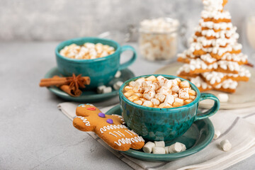 Hot drink with marshmallows and candy cane in cup on texture table.Cozy seasonal holidays.Hot cocoa with gingerbread Christmas cookies.Hot chocolate with marshmallow and spices.Copy space.